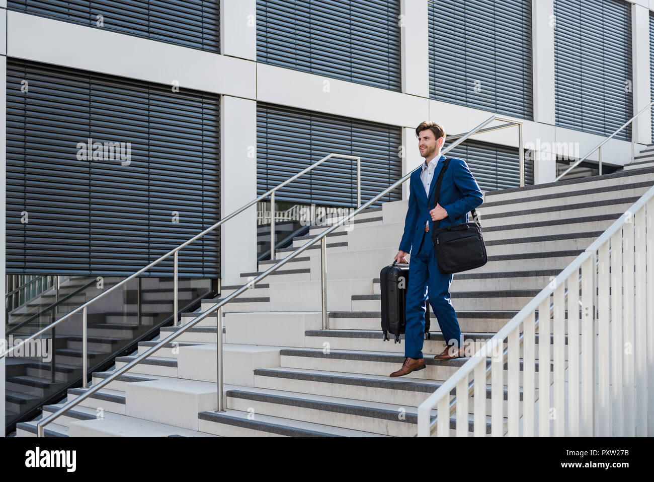 Lächelnd Geschäftsmann mit Gepäck in der Stadt Treppen hinunter. Stockfoto