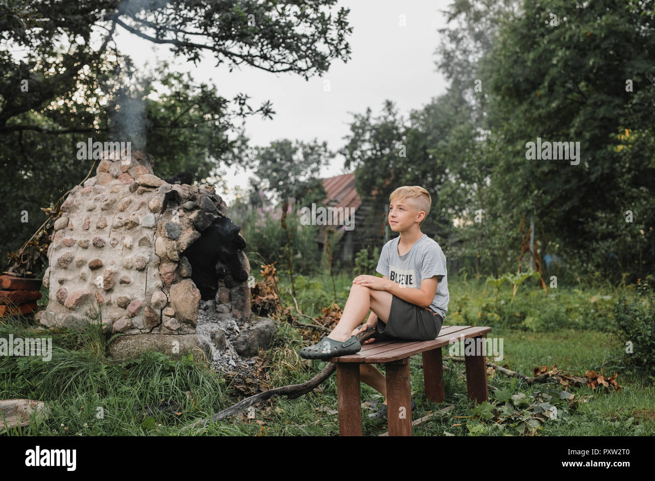 Junge entspannen auf Holzbank im Garten Stockfoto