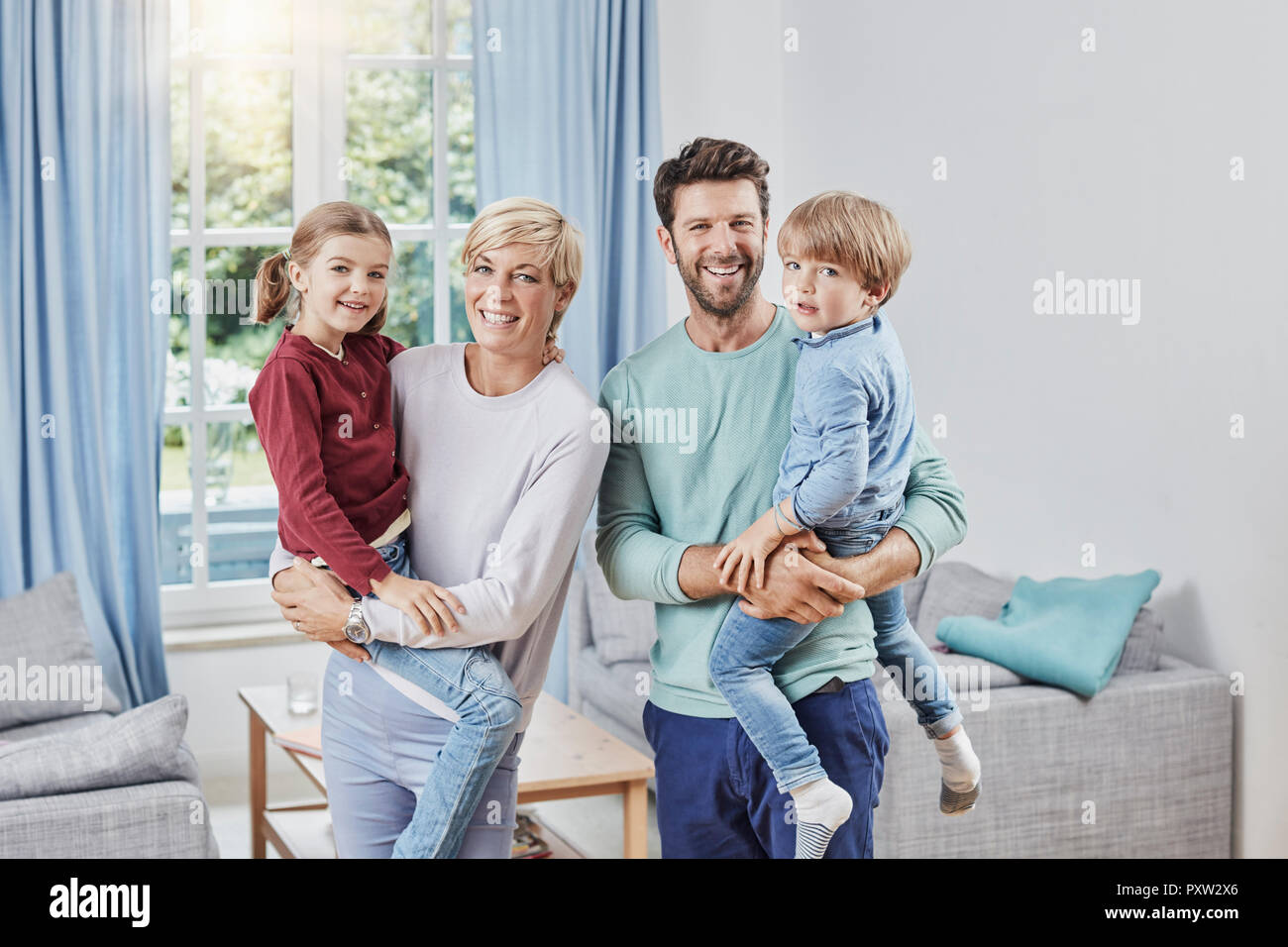 Portrait der glücklichen Familie mit zwei Kindern zu Hause Stockfoto