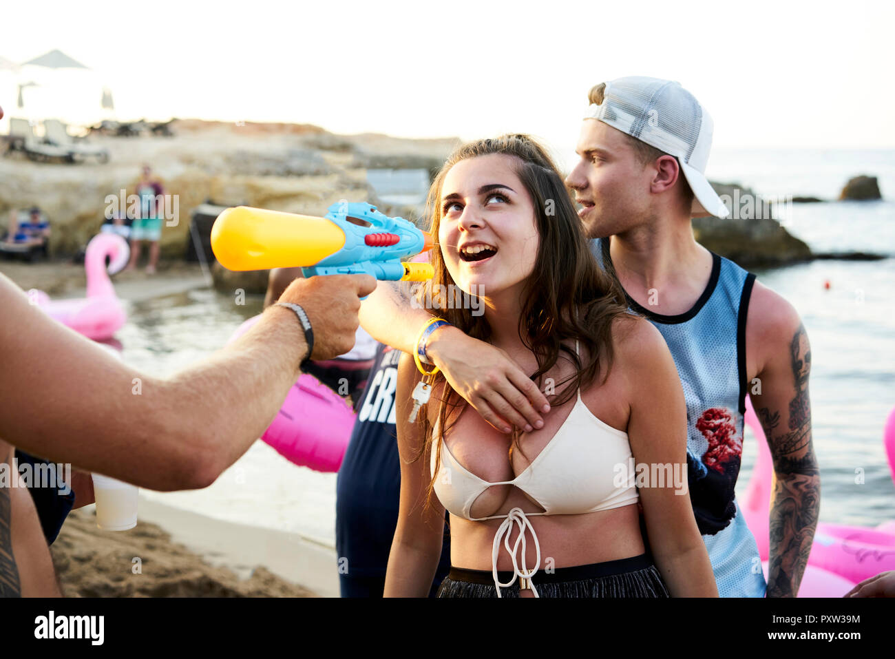 Kreta, Chersonisou, Beach Party, Frau, tequila Shot mit Wasserpistole, Mann sie von hinten umarmt Stockfoto