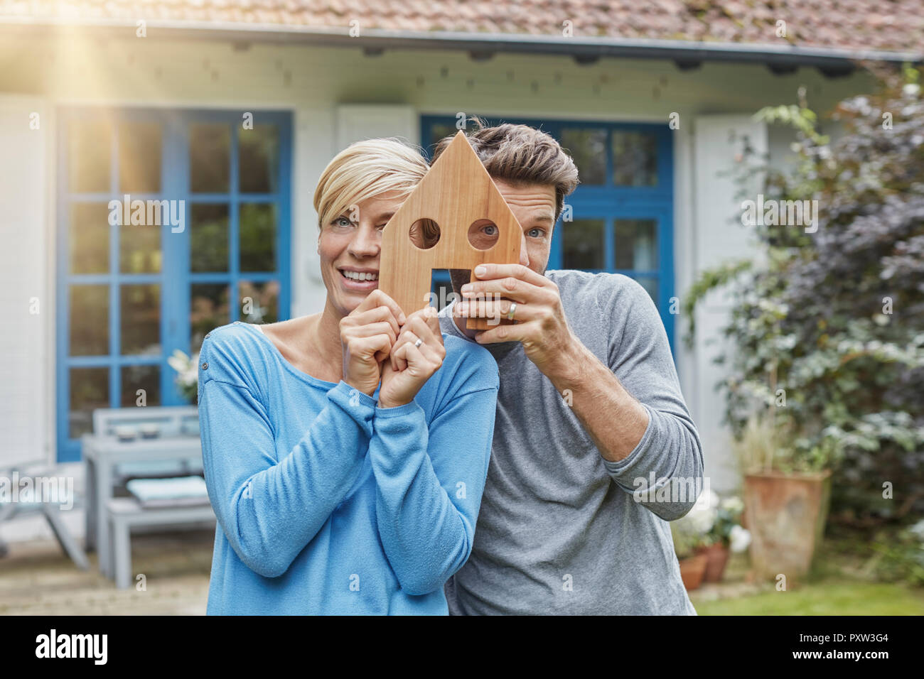 Portrait von lächelnden Paar steht vor ihrem Haus holding Haus Modell Stockfoto