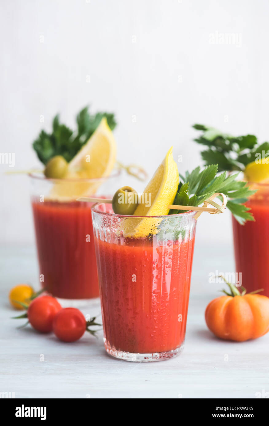 Gläser frisch würzig Tomatensaft mit cellery garniert mit Zitronenscheibe, grünen Oliven und Petersilie Stockfoto