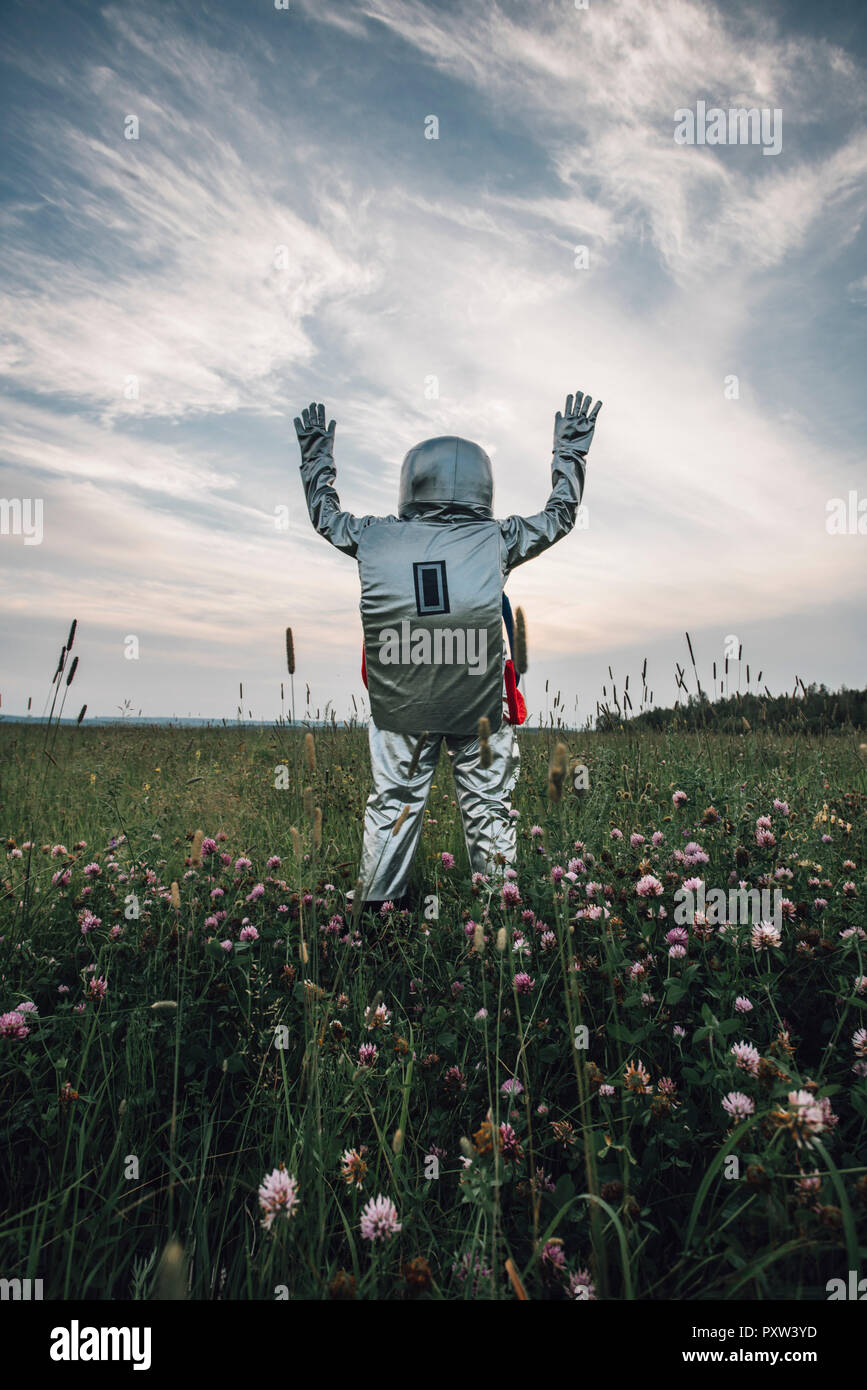 Spaceman erkunden Natur, stehend in der Wiese, winken Stockfoto