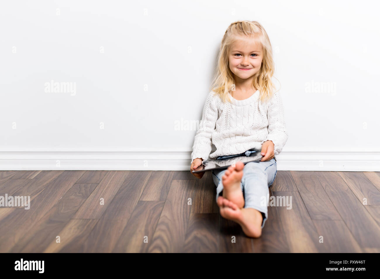 Ein Kind mit Tablet liegen auf dem Boden. Mädchen spielen Laptop Stockfoto