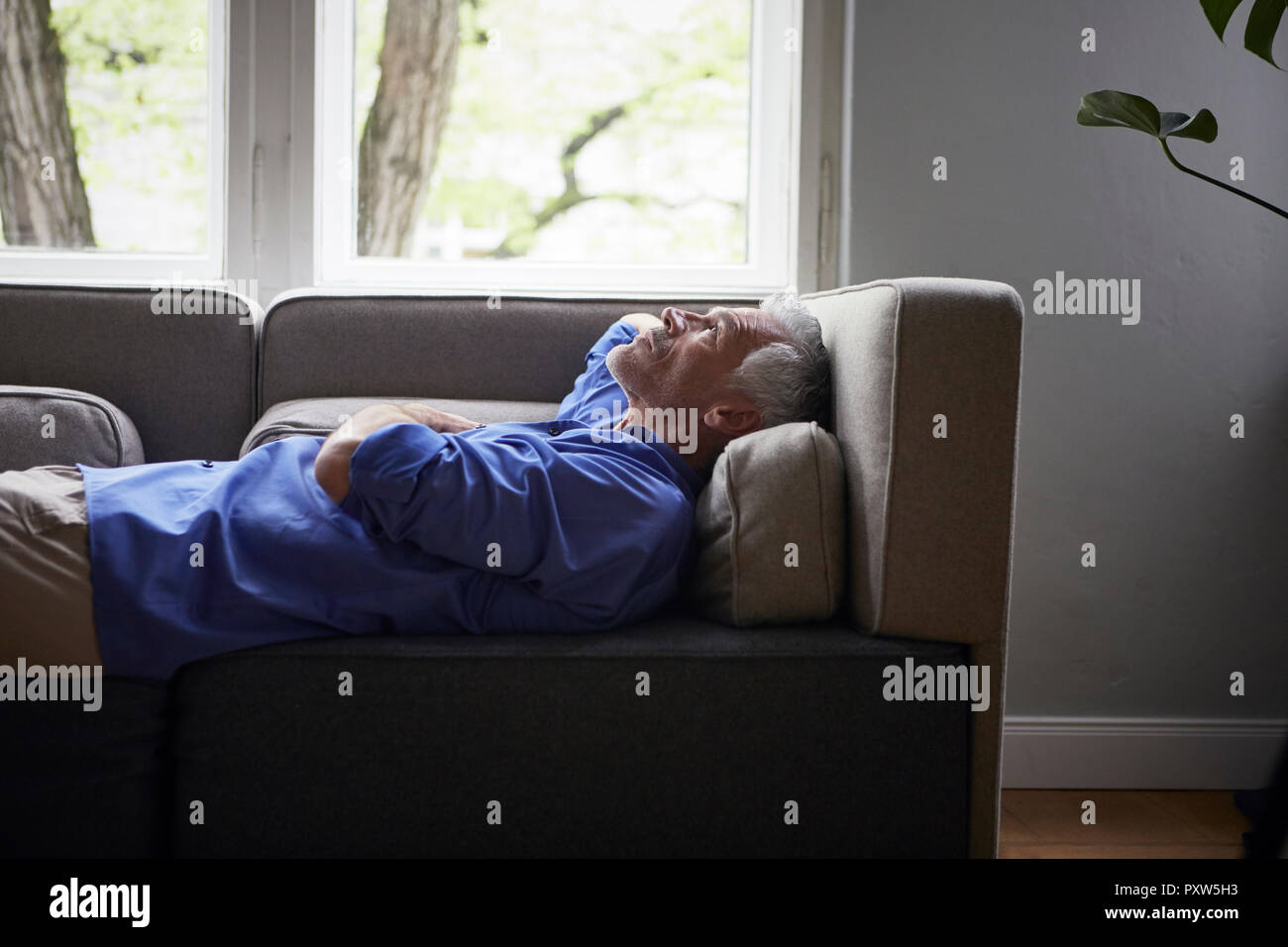 Reifer Mann zu Hause auf der Couch liegend Stockfoto