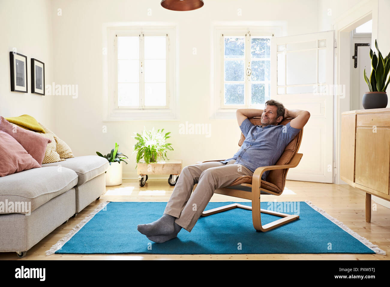 Mann entspannt zu Hause im Sessel sitzen Stockfoto