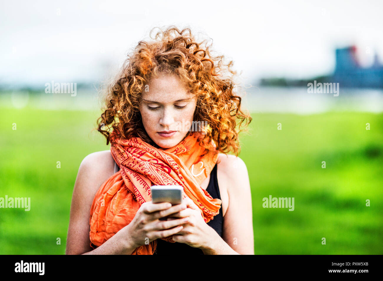 Porträt der jungen Frau mit dem lockigen Haar an Zelle Telefon Stockfoto