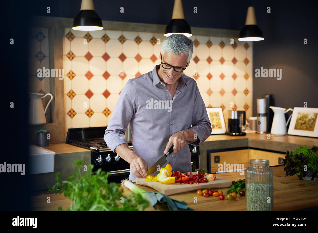 Lächelnd reifer Mann zu hacken, Paprika in der Küche Stockfoto