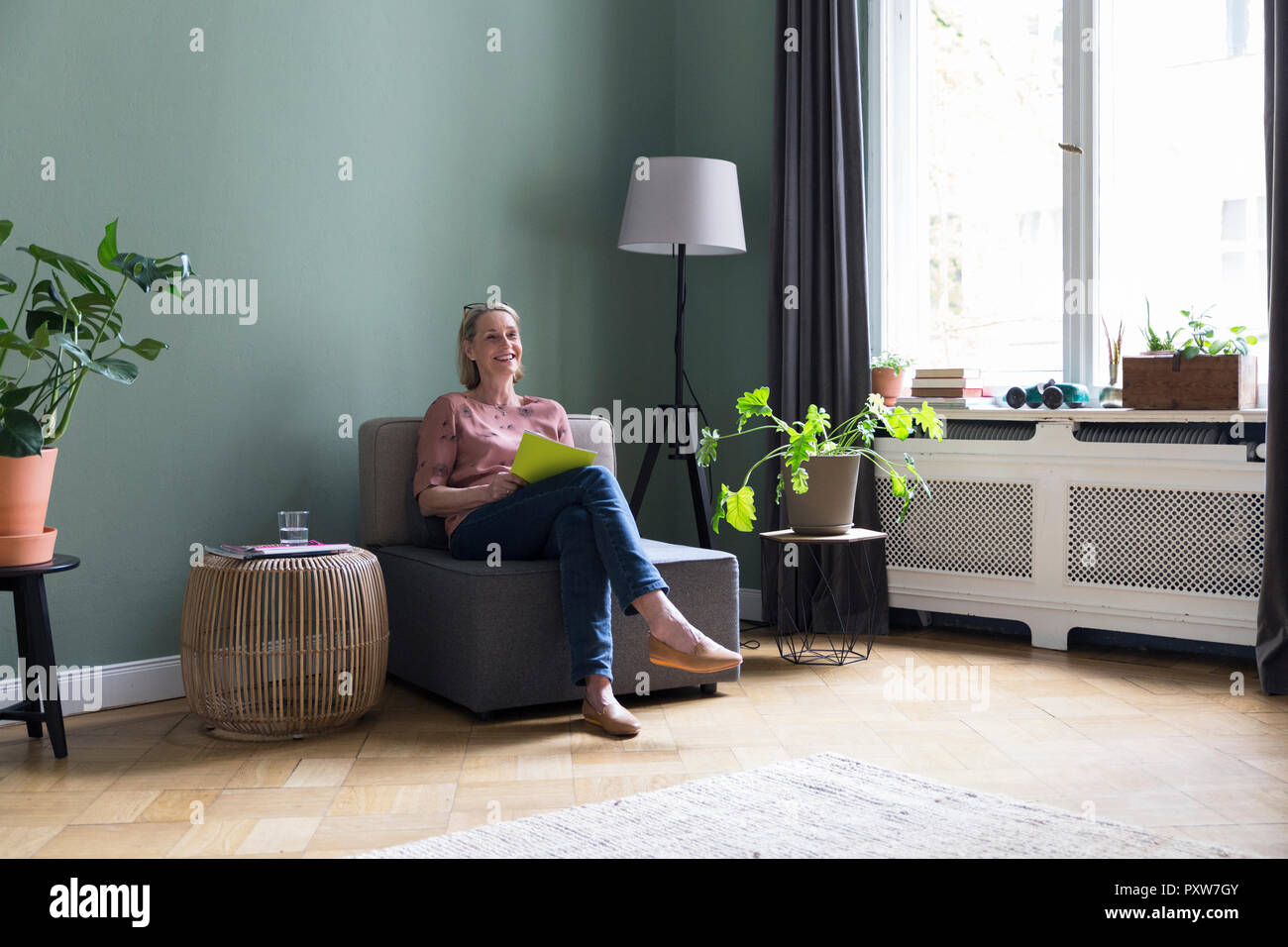 Lächelnd reife Frau zu Hause sitzen Stockfoto