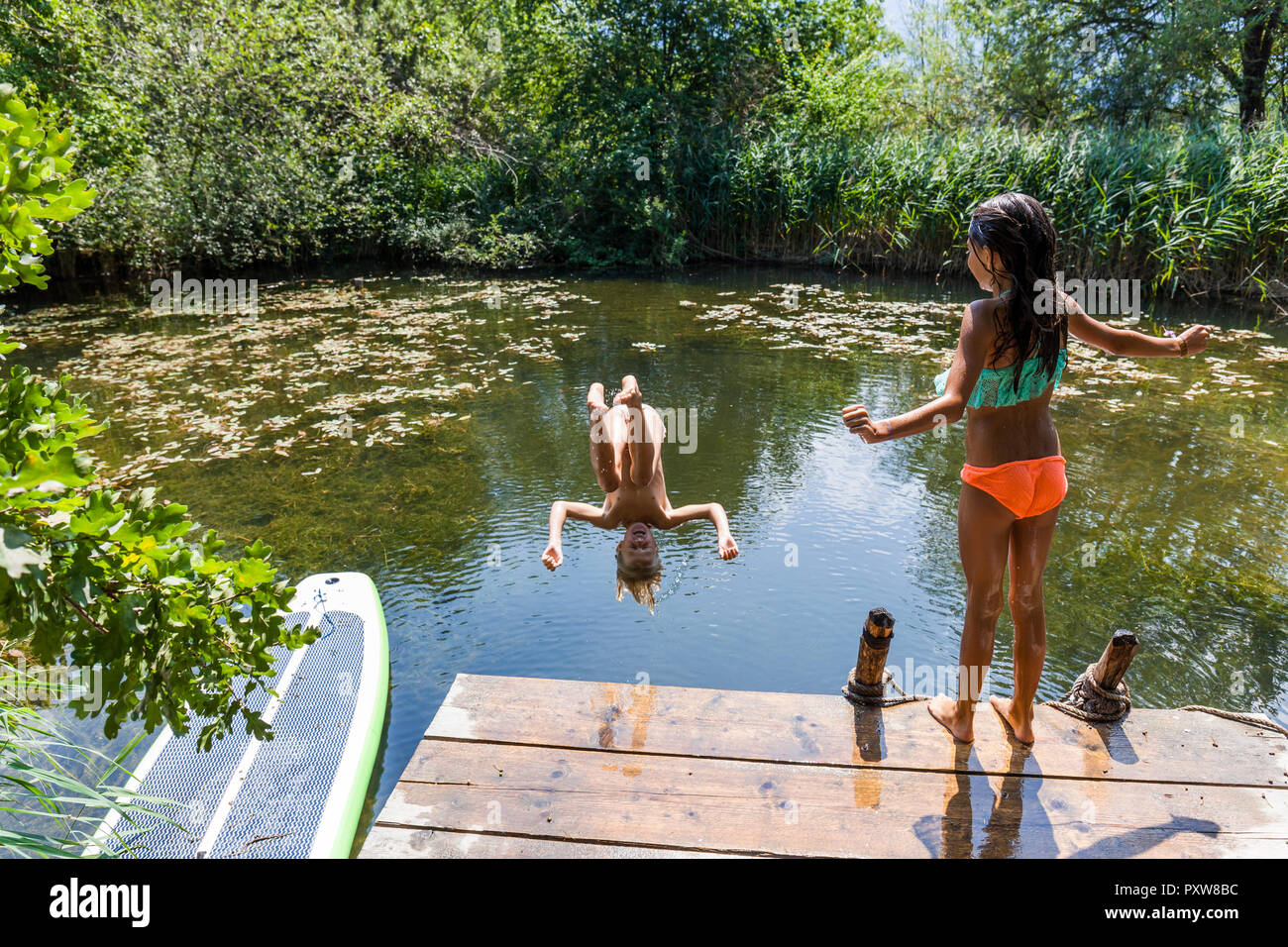 Mädchen schauen Ihren Freund in den Teich springen Stockfoto