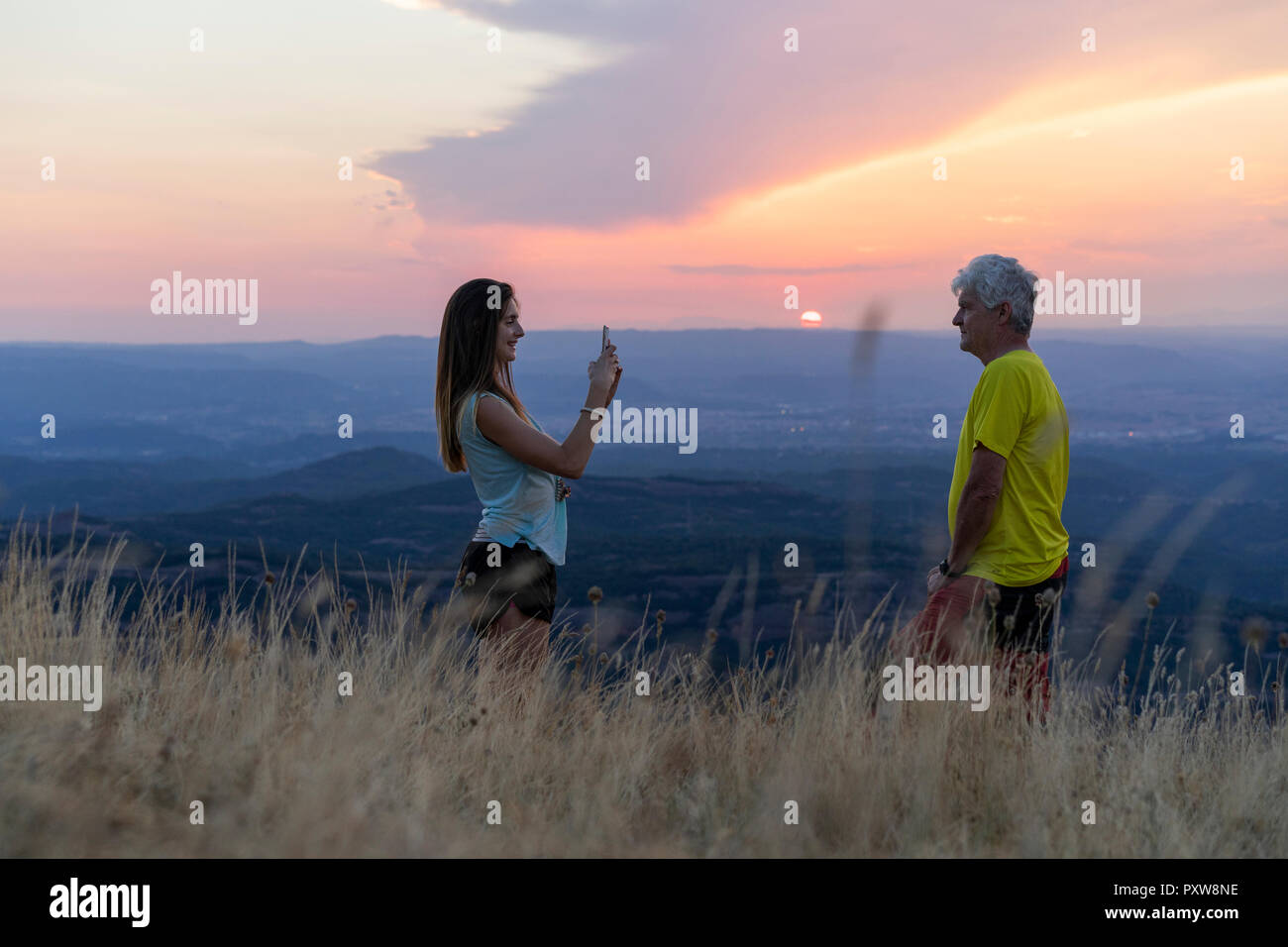 Spanien, Katalonien, Montcau, Senior Vater und Tochter, die ein Handy Bild auf dem Hügel bei Sonnenuntergang Stockfoto