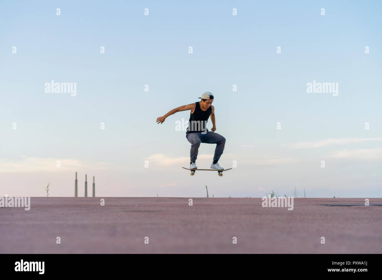 Junger Mann, ein Skateboard Trick auf eine Spur in der Dämmerung Stockfoto