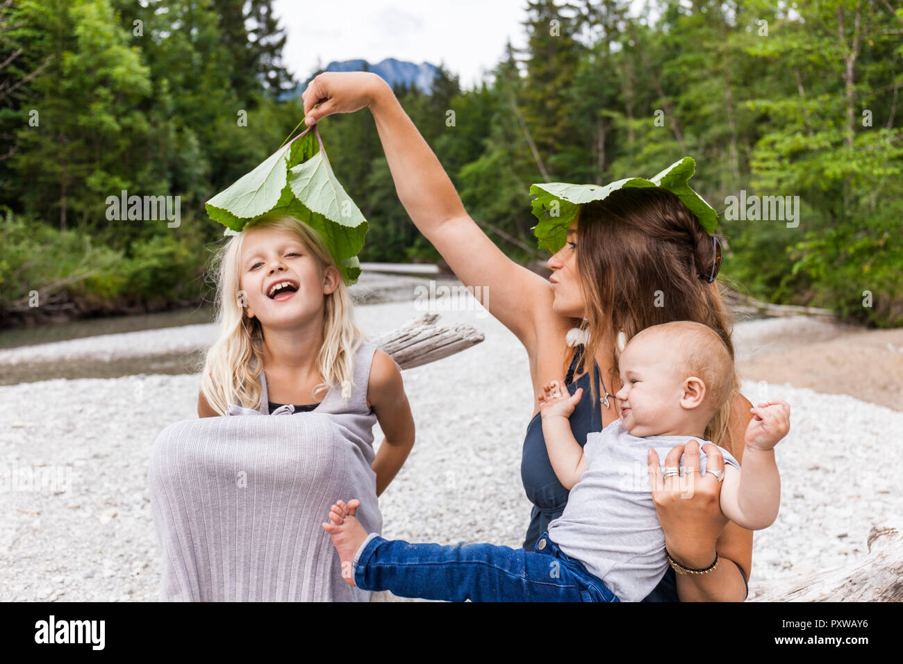 Mutter mit zwei Kindern beim Spielen mit Blättern am Flußufer Stockfoto