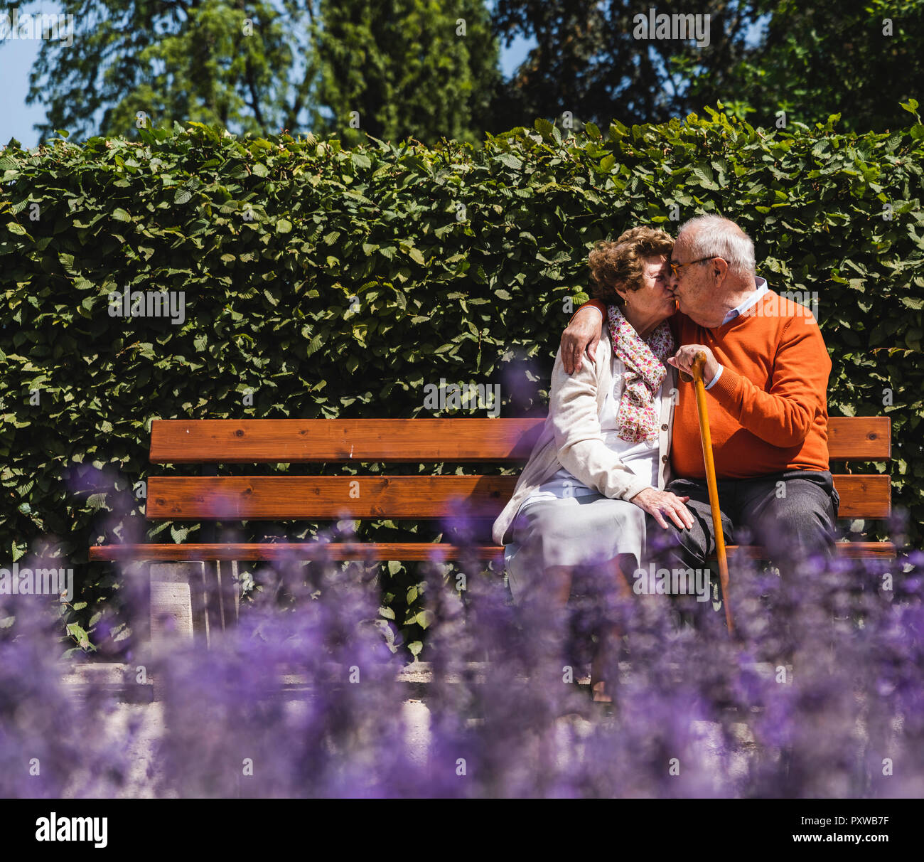 Senior Paar sitzt auf der Bank im Park, küssen Stockfoto