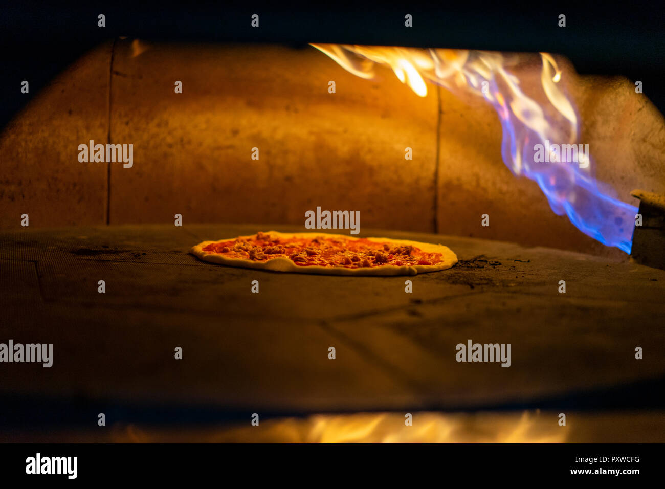 Pizza in Ofen mit brennenden Flamme Stockfoto