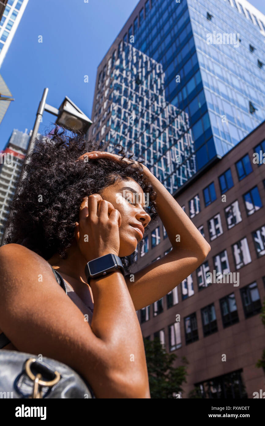 Deutschland, Frankfurt, Porträt der jungen Frau mit smartwatch am Telefon vor der Wolkenkratzer Stockfoto
