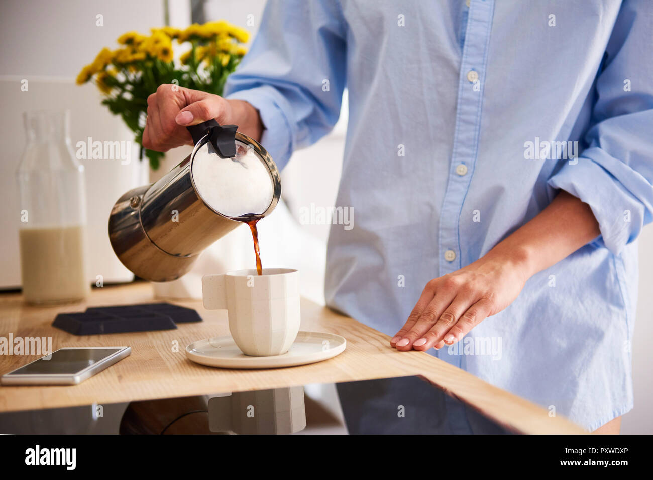 Junge Frau Kaffee in der Tasse gießen Stockfoto