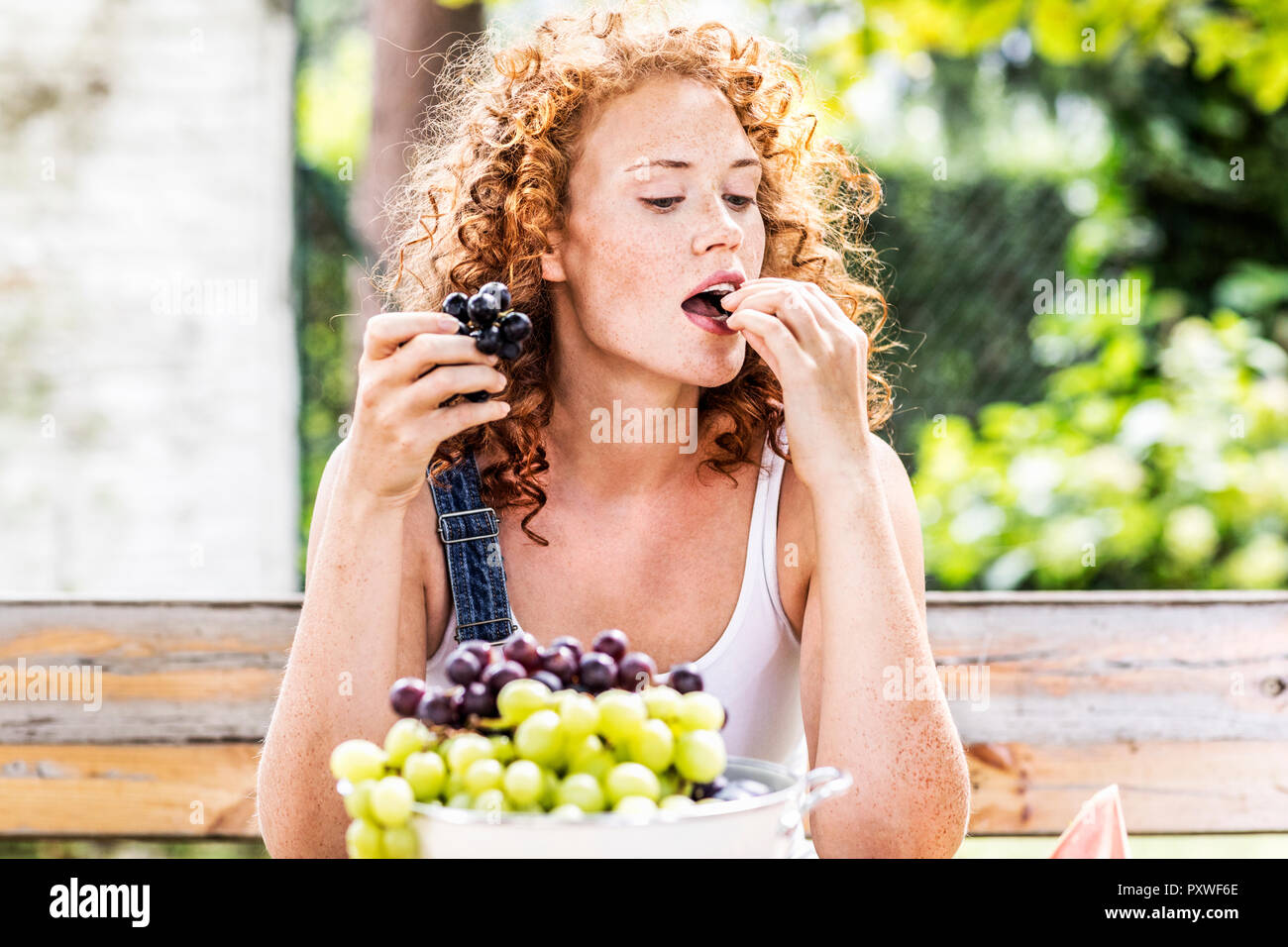 Porträt der rothaarige junge Frau Trauben essen Stockfoto