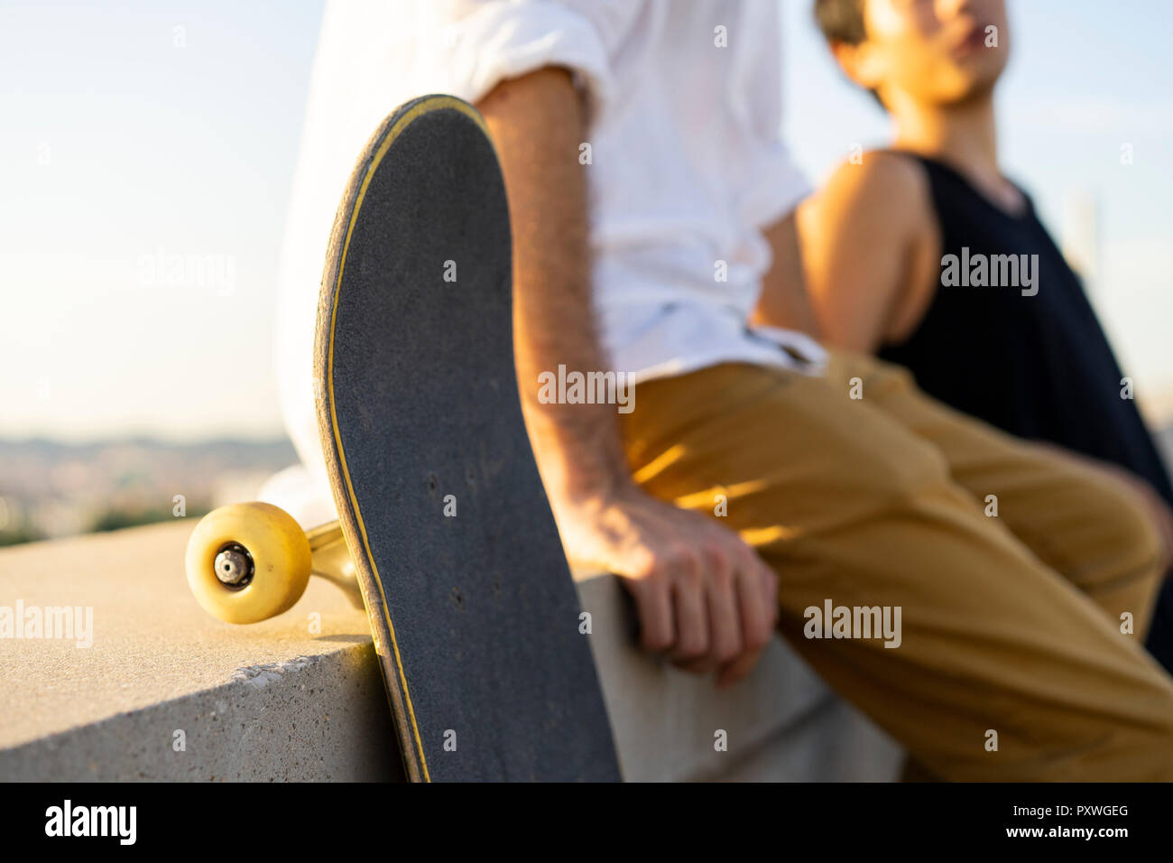 Close-up von zwei jungen Männern mit skateboards sitzen auf einer Mauer Stockfoto