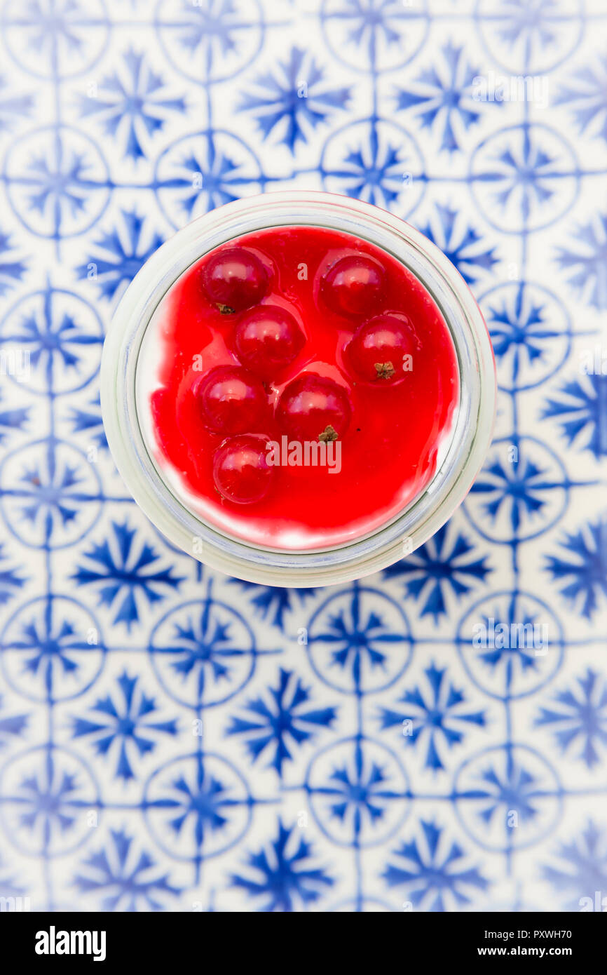 Griechischer Joghurt mit roten Johannisbeeren Sauce auf blau gemusterten Fliesen Stockfoto