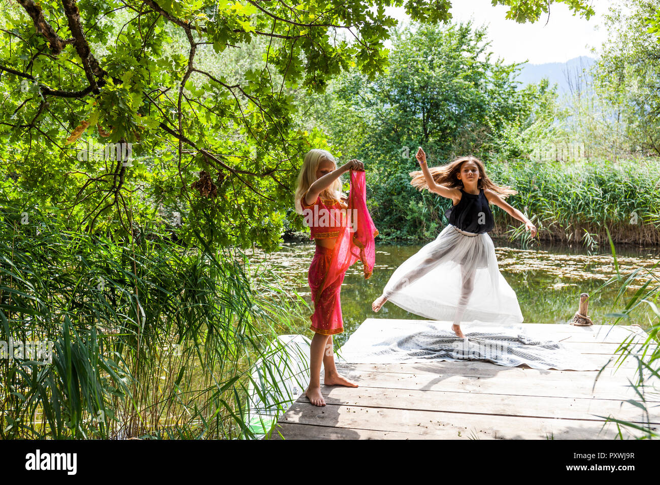 Zwei Mädchen auf Mole in einem Teich in Kostüme Stockfoto