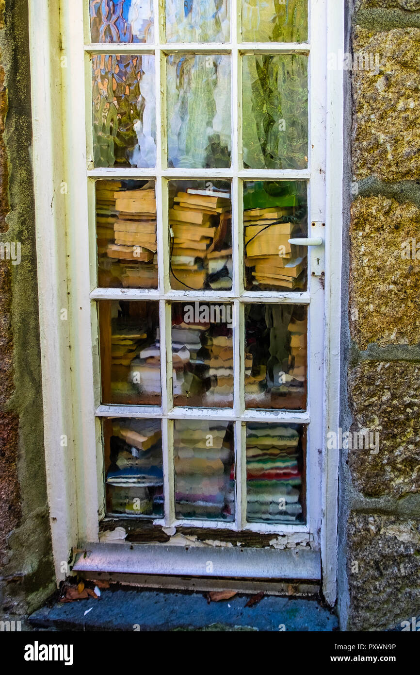 Fenster Stil Tür mit unverständlichen Stil Glasscheiben, vollständig mit Hunderten von Büchern aller Größen in hohen Stapeln blockiert Stockfoto