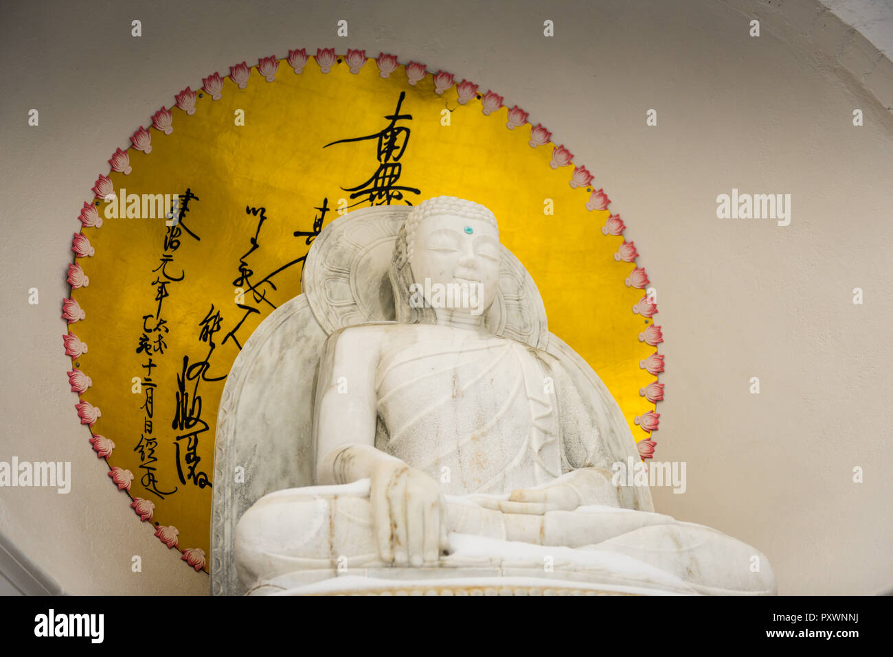 Golden Orb und Buchstaben Surround weißer Marmor Buddha bei Grafton Frieden Pagode in Upstate New York sitzt. Stockfoto