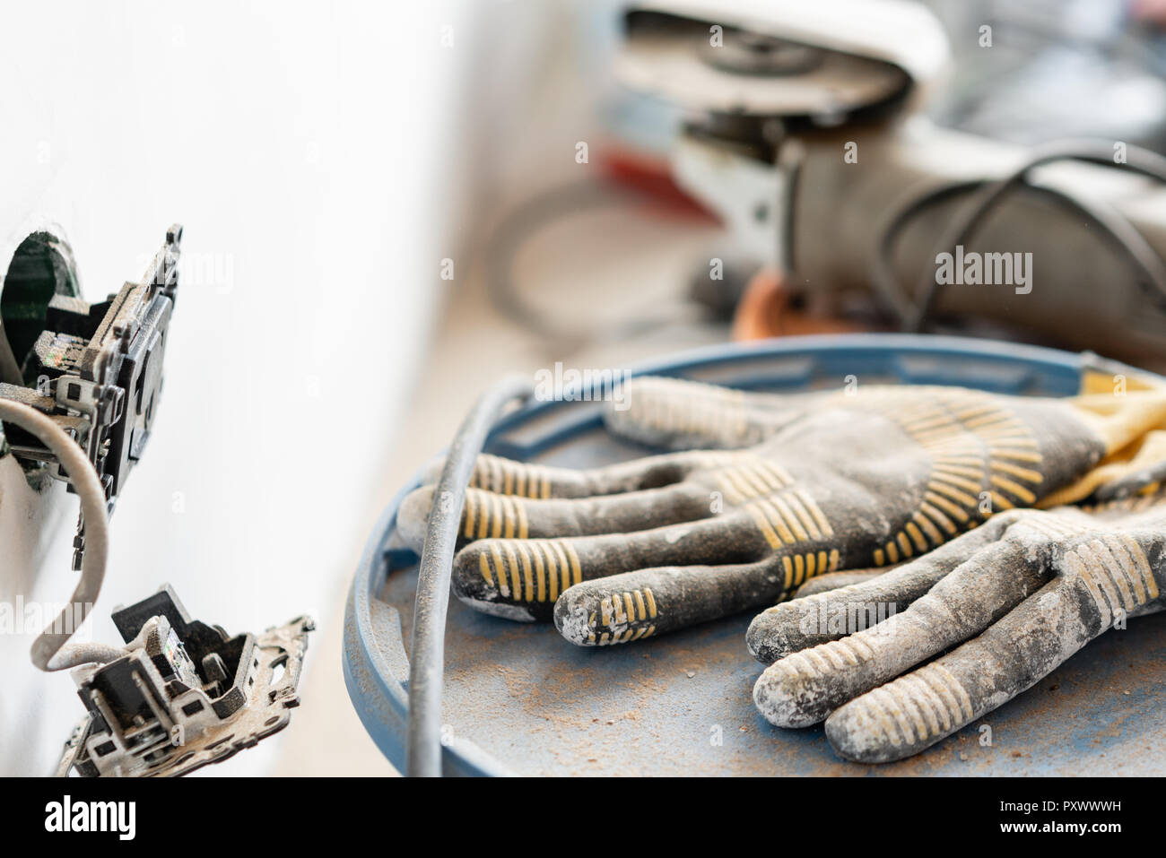 Arbeitshandschuhe im Vordergrund. Viele Werkzeuge und Farbdosen im Hintergrund. Konzept der Reparatur im Haus Stockfoto