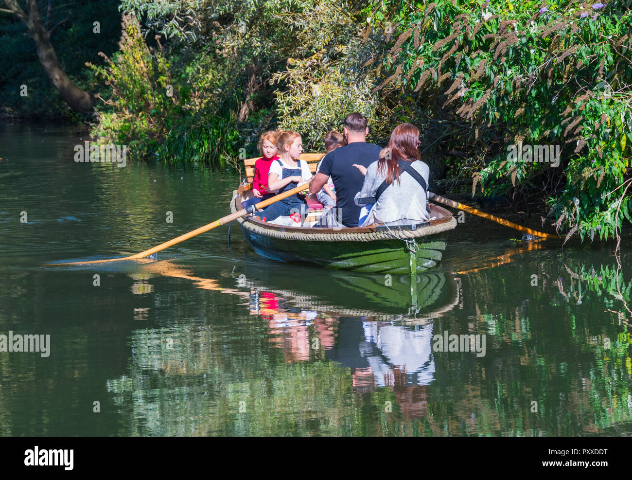 Familie in einem kleinen Ruderboot Reflexionen im Wasser auf einem Kanal im Herbst, UK. Stockfoto