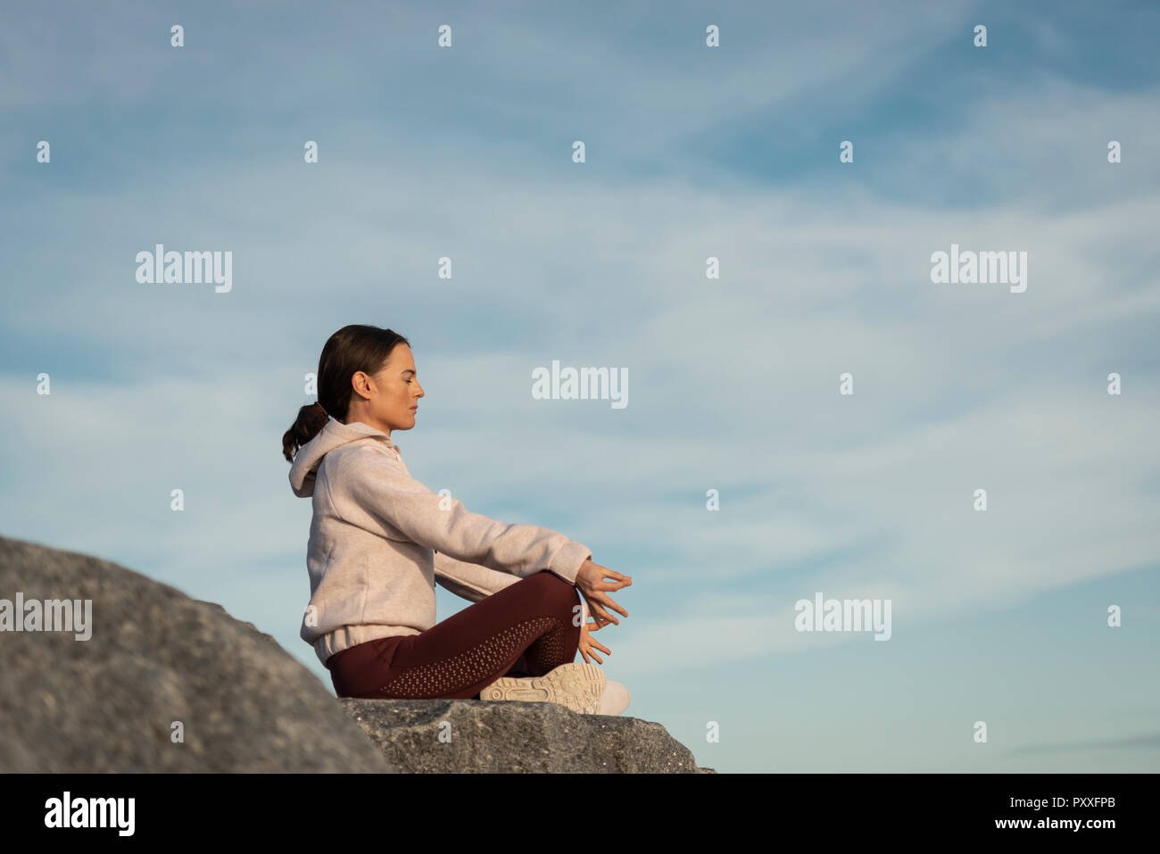 Frau sitzt gekreuzten Beinen, meditierend sitzt auf einem Boulder Stockfoto