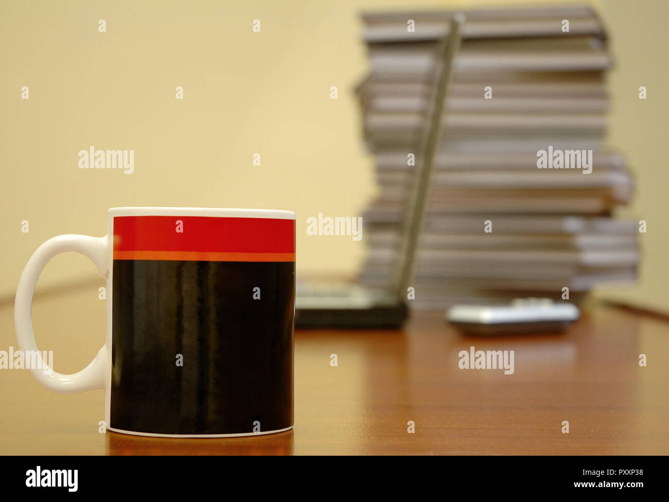 Kaffeebecher, stehend auf einem Schreibtisch, Laptop und Bücher Stockfoto