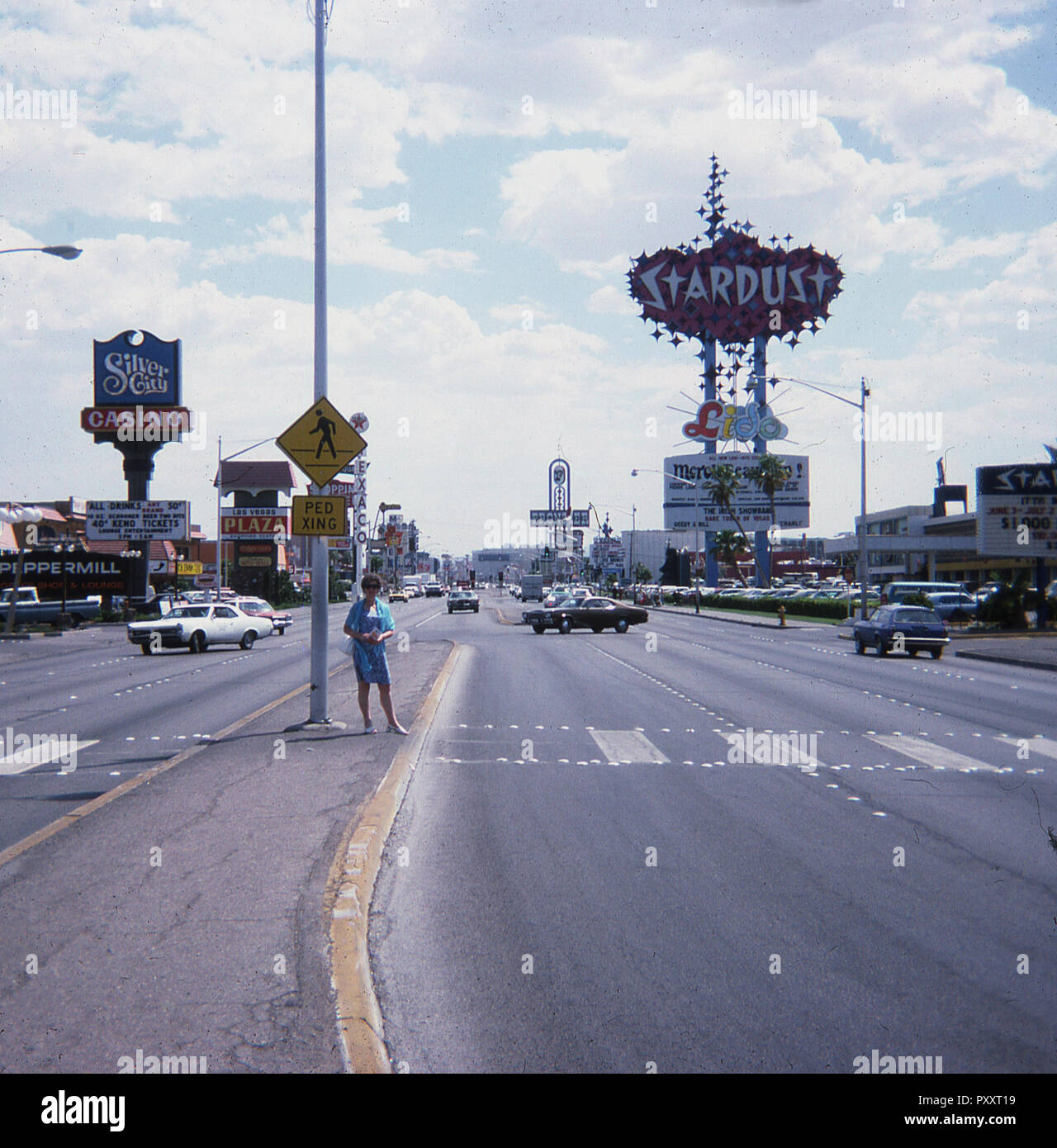 1975, historische, Tages- und eine Dame in der Mitte der "Flaniermeile", einer zentralen Boulevard im Casino der Stadt von Las Vegas, Nevada, USA steht. Ein Schild am Straßenrand (1967) für die "Sternenstaub", dem berühmten Resort Hotel und Casino, das 1958 eröffnet wurde, kann auf dem Bild zu sehen und wurde von einer Streuung von Neon Sterne formen, die nachts beleuchtet. Stockfoto 1975, historische, Tages- und eine Dame in der Mitte der "Flaniermeile", einer zentralen Boulevard im Casino der Stadt von Las Vegas, Nevada, USA steht. Ein Schild am Straßenrand (1967) für die "Sternenstaub", dem berühmten Resort Hotel und Casino, das 1958 eröffnet wurde, kann auf dem Bild zu sehen und wurde von einer Streuung von Neon Sterne formen, die nachts beleuchtet. Stockfoto