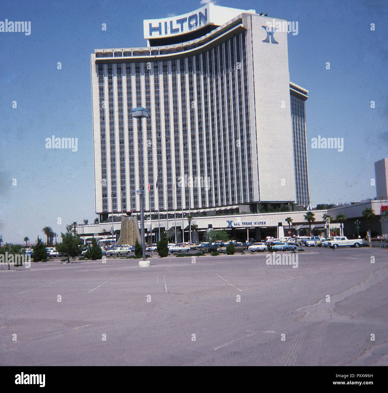 Las Vegas, Nevada, USA, 1975, Äußere des Hllton Hotel, Gebäude und Parkplatz. Ursprünglich die "Internationale", als es 1969 eröffnet wurde Nevada's höchste Gebäude bezeichnet. Es war das Las Vegas Hilton 1971 umbenannt. Dieses Bild wurde vor dem späteren Ergänzungen der Hotel, sah es 1981 werden das größte Hotel der Welt. Das Hotel berühmt für unter anderem ist, Elvis es durchführen, der für sieben Jahre im Hotel erschienen, umfasst 636 aufeinanderfolgenden ausverkauften Shows. Stockfoto
