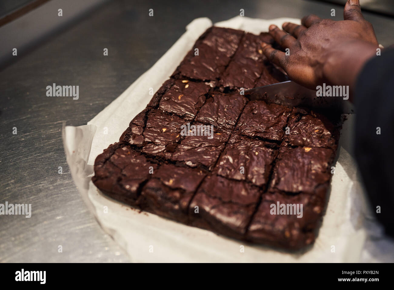 Bäcker schneiden Brownies in Quadrate in einem Cafe Küche Stockfoto