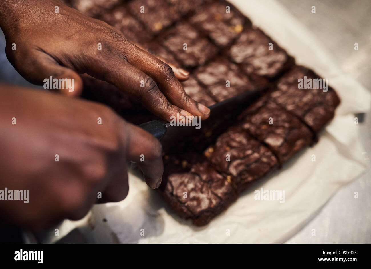 Baker slicing frischen Brownies in Quadrate in einem Cafe Küche Stockfoto