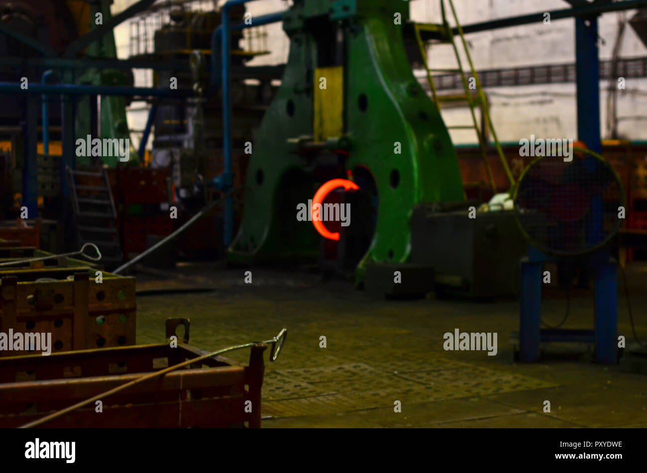 Detail - Teil einer Maschine. Heiße Eisen in den weiterverarbeitenden Betrieben, die ein Arbeitnehmer statt. Metallurgische Werk industrial Workshop mit offenen Kamin Ofen und Himmel Stockfoto