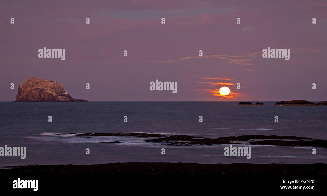 North Berwick, East Lothian, Schottland, Großbritannien. 24 Okt, 2018. Hunter's Moon Rising neben den Bass Rock und der Himmel, der die Farbton- und reflektiert die Farben der herrlichen Sonnenuntergang, das gegenüber auftrat. Stockfoto