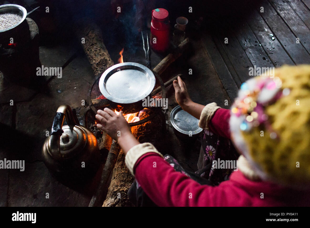 Arme Frau sitzen vor dem Hallenbad Lagerfeuer und wärmende Hände, Myanmar, Shan, Myanmar Stockfoto
