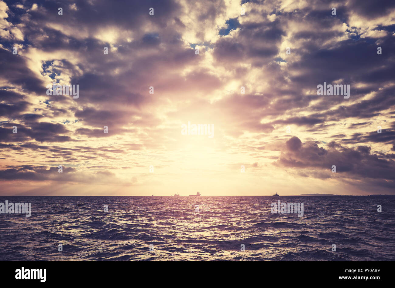 Malerische dramatische Meereslandschaft mit Schiffen über den Horizont bei Sonnenuntergang, Farbe getonte Bild. Stockfoto