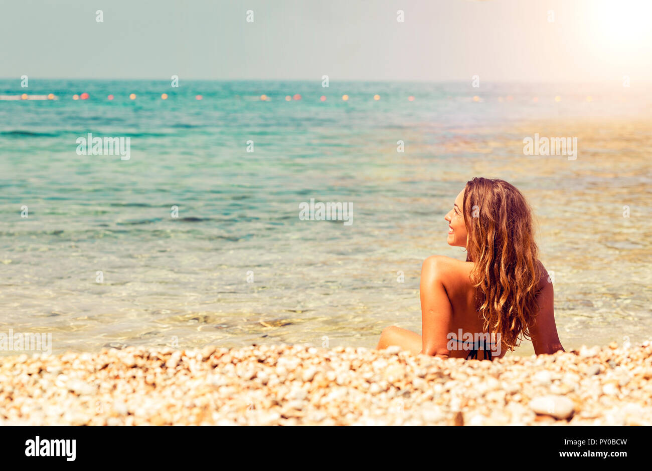 Schöne junge Frau am Strand bei Sonnenuntergang auf dem Rücken liegend Stockfoto