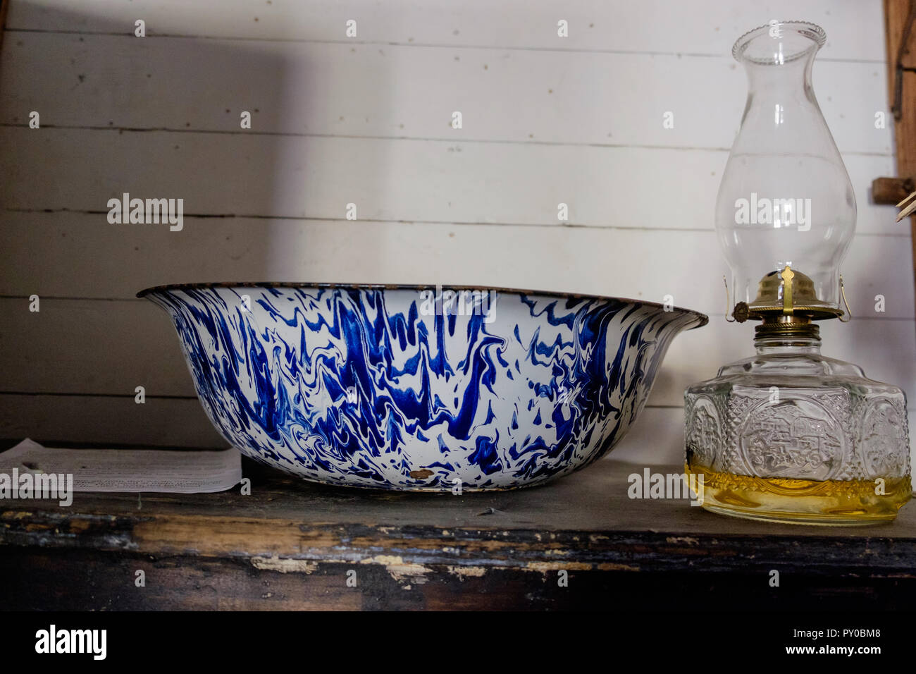 Porzellan blau und weiß Waschbecken & Alte Öllampe auf Holztisch im Inneren des Hauses in der Chestnut Square Historic Village, McKinney Texas. Stockfoto