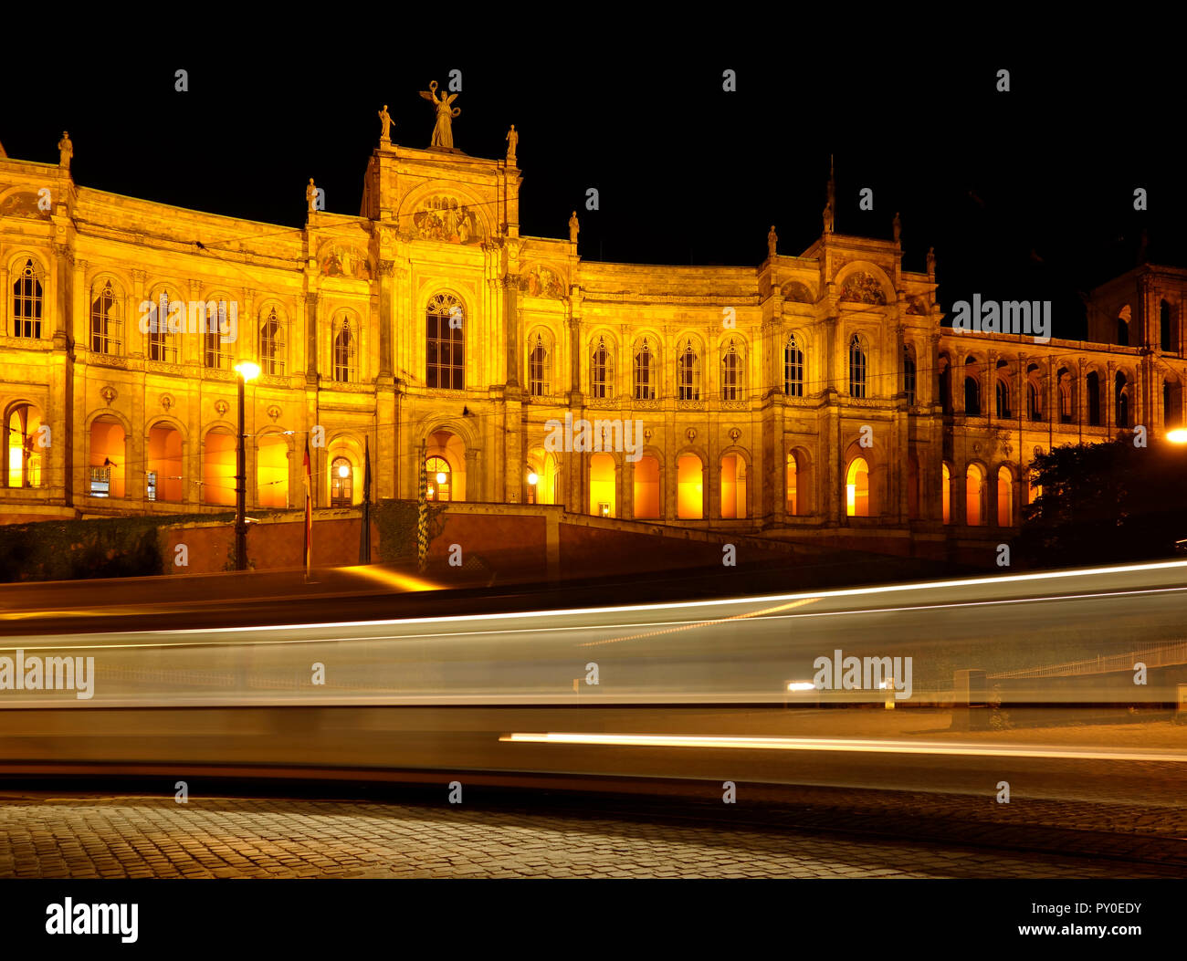 Das historische Gebäude Maximillianeum in München, Stadt in Bayern, Teil von Deutschland bei Nacht mit Lichtstrahlen von einem vorbeifahrenden Straßenbahn durch lange Belichtung Stockfoto