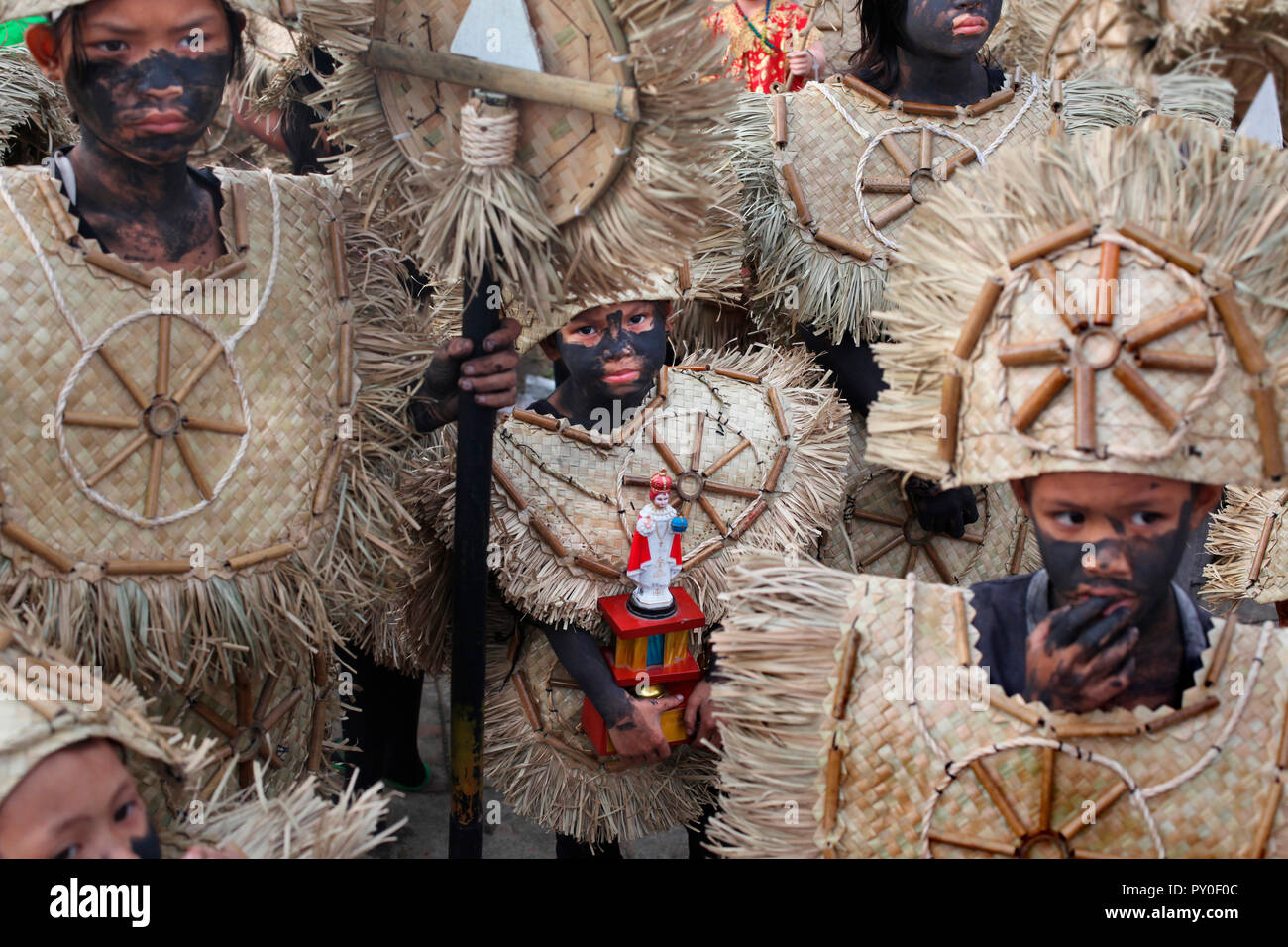 Junge Mädchen in einer Gruppe von Kindern, das Tragen von Tribal Kostüme, holding Santo Nino figurine bei Ati Atihan Festival, Kalibo, Aklan, Panay Island, Philippinen Stockfoto