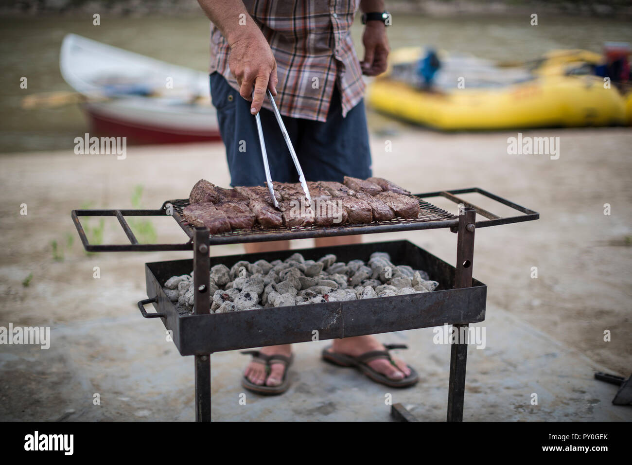 Bootsführer mit Steaks vom Grill in der Küche im Freien während des Green River Rafting Trip Wüst/Grau Canyon, Utah, USA Stockfoto