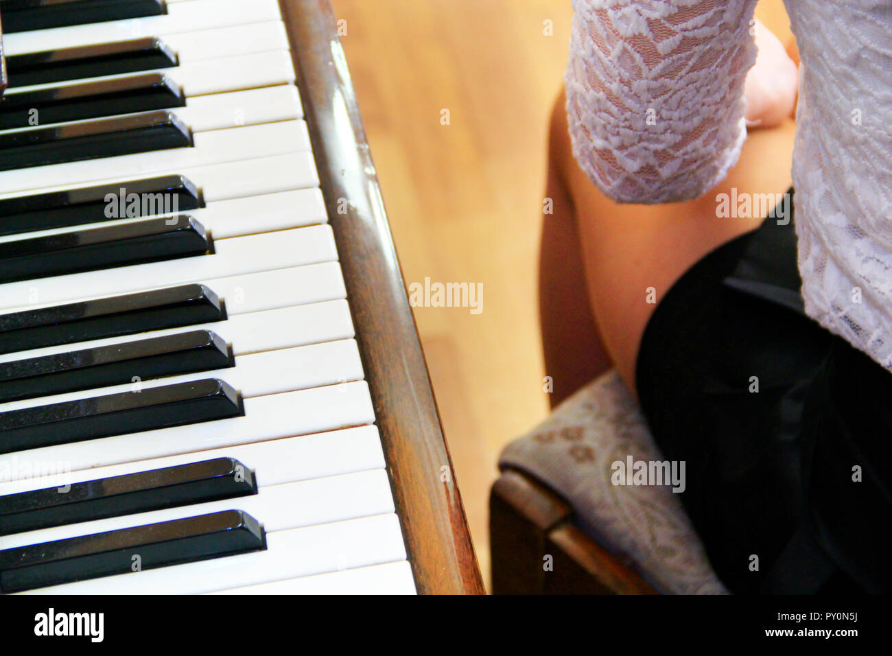 Beine der junge Pianist Mädchen neben Klavier. Piano keys und Beine der Pianist Mädchen. Tastatur Musikinstrument. Musik Konzept Stockfoto