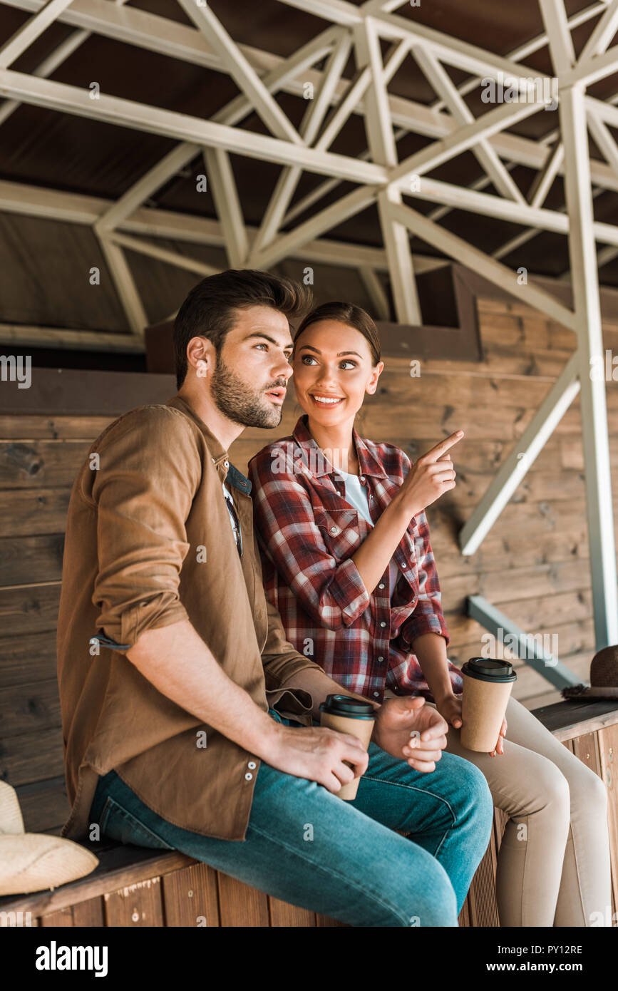 Cowboy und Cowgirl sitzend mit Kaffee an der Ranch zu gehen, Frau zeigt auf etwas Stockfoto
