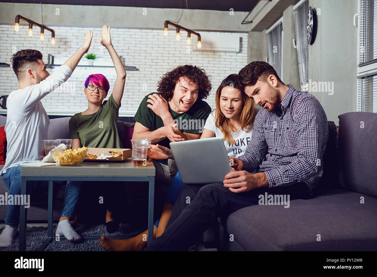 Eine Gruppe von Freunden der Schüler in Freizeitaktivitäten mit einem Laptop in einem roo Stockfoto