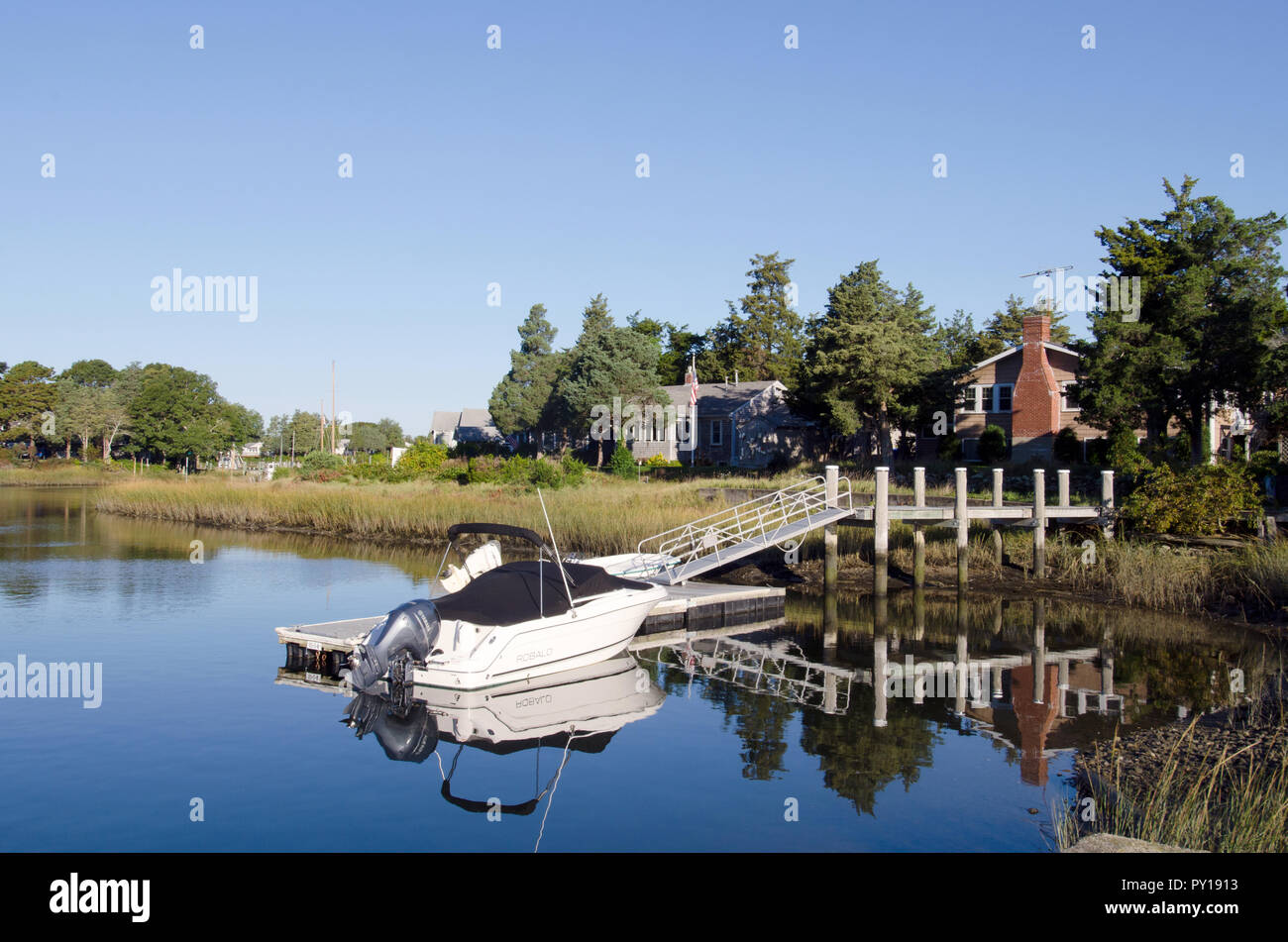 Ein Boot auf einem Dock an einem Haus auf der Pocasset Fluss, die Buzzards Bay, Pocasset, Cape Cod, Massachusetts, USA führt Stockfoto