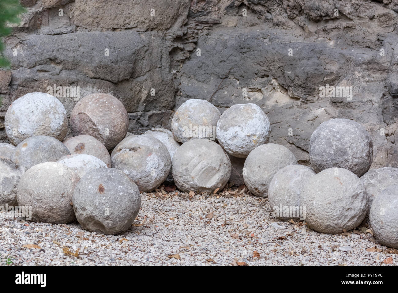 Alte Kanonenkugeln aus grauem Stein liegend auf die Kieselsteine am Fuße des Felsens. Stockfoto