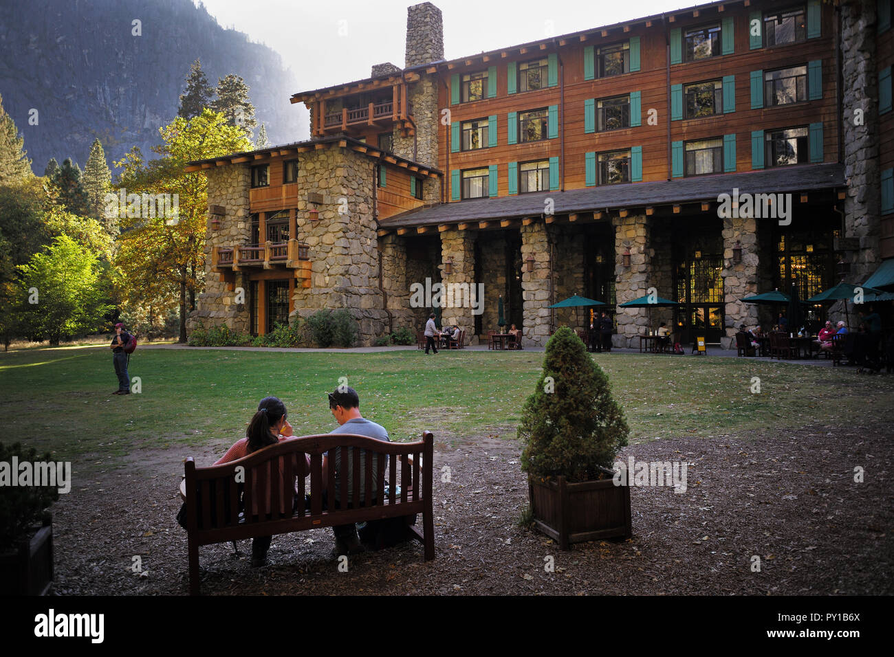 Gäste des The Majestic Hotel Yosemite oder Ahwahnee Hotel, sitzen auf einer Bank in der Nähe des Eingangs. Stockfoto